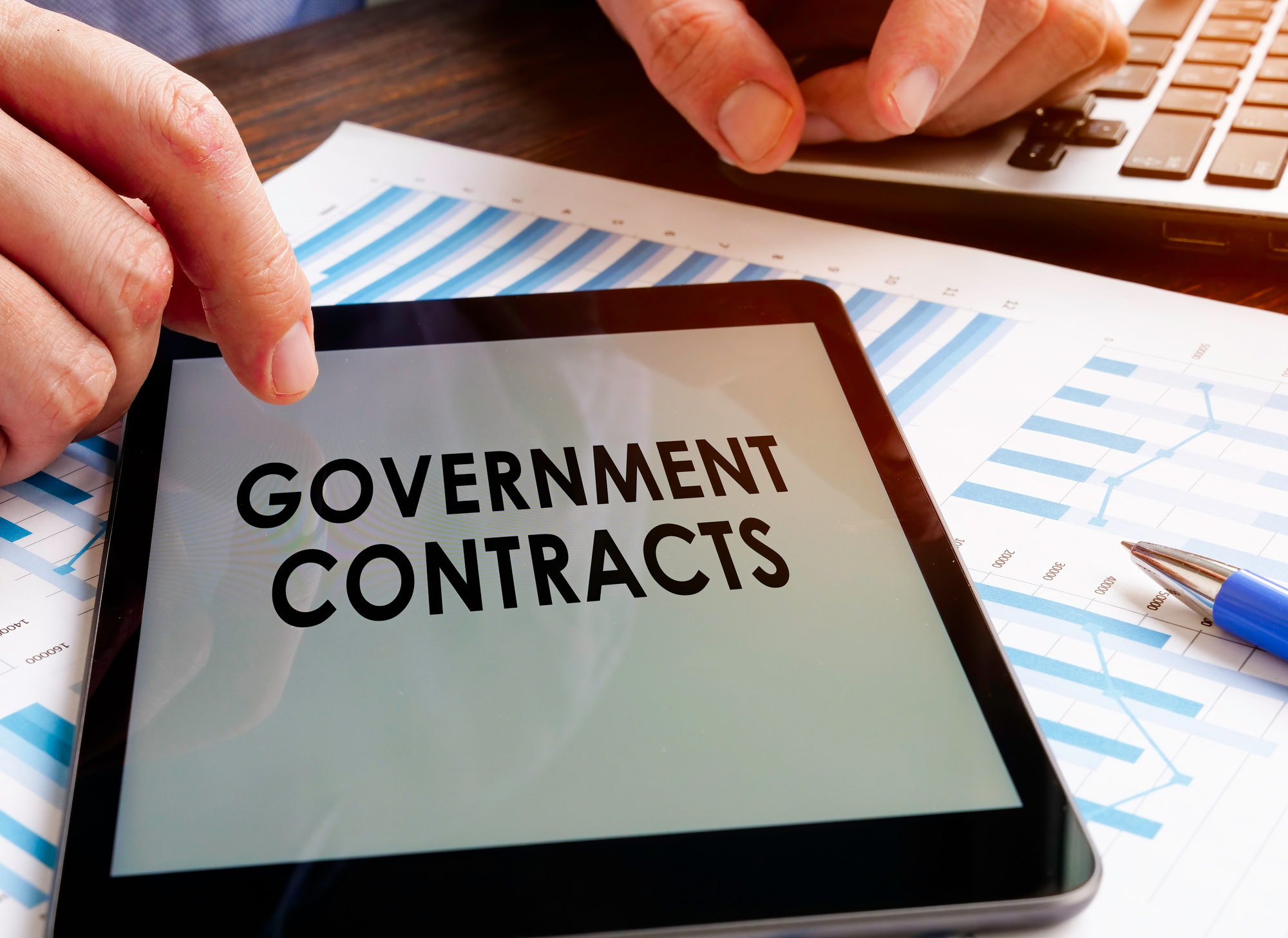 A man shows information about government contracts on a tablet.